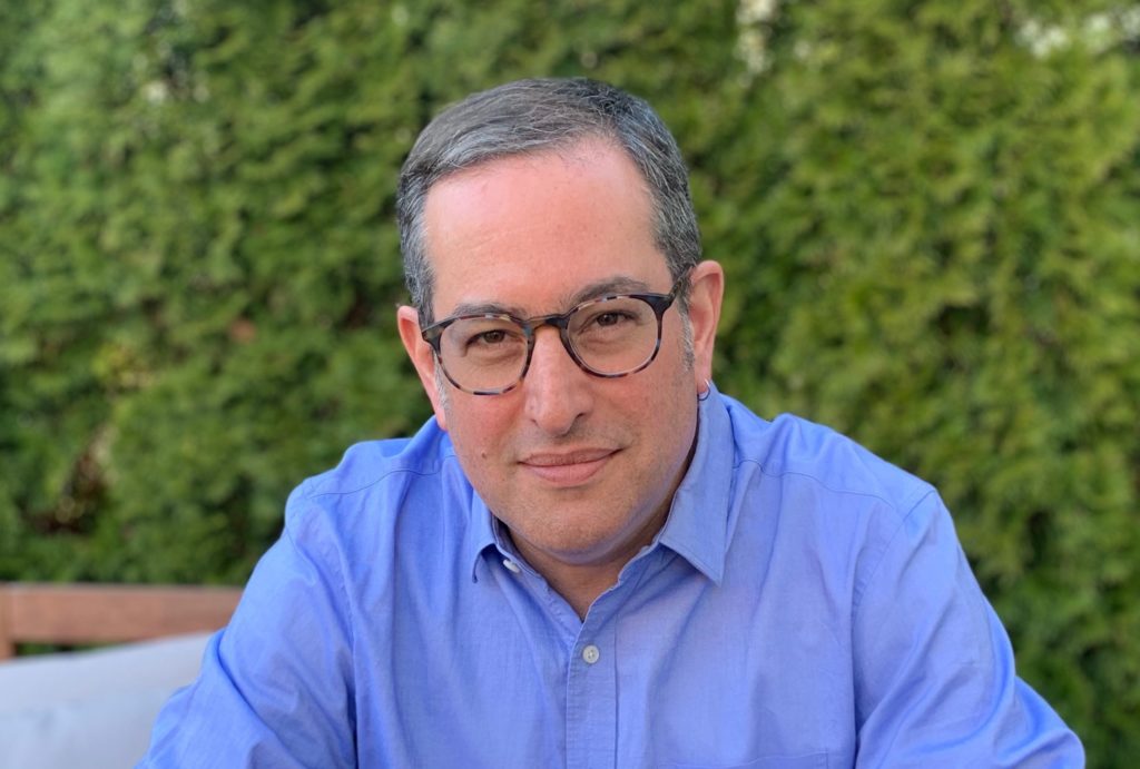 Seth Klein sits in front of some bushes