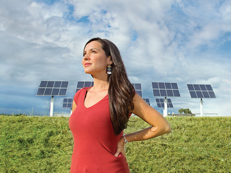 Melina Laboucan-Mossimo stands in front of a row of solar panels