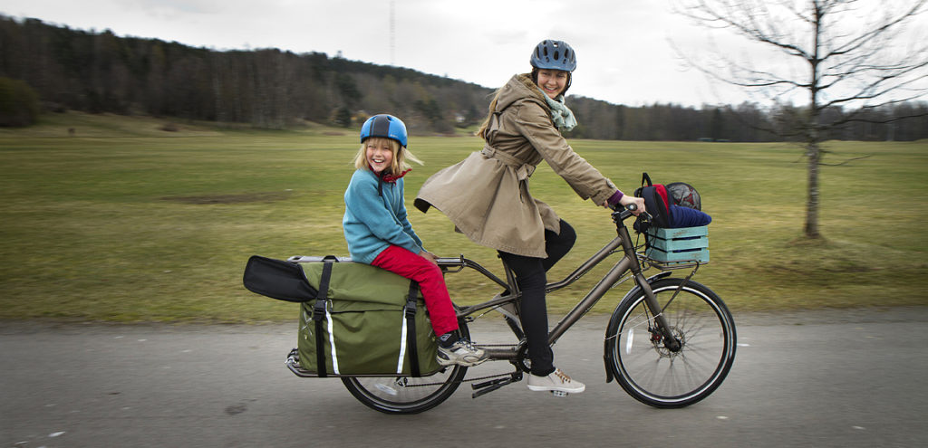 Woman rides cargo bike with kid