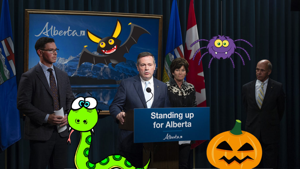 Jason Kenney making a speech at a podium with cartoon pumpkin, bat, and snake around him.