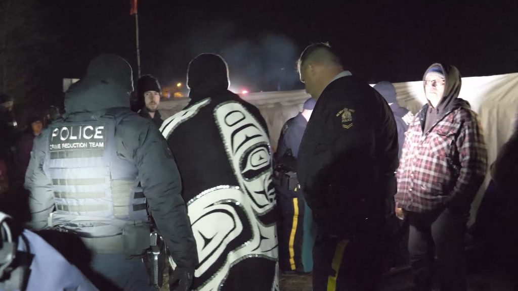 Gitxsan hereditary chief Spookw (in regalia) is arrested by the RCMP on his own territory in February 2020.