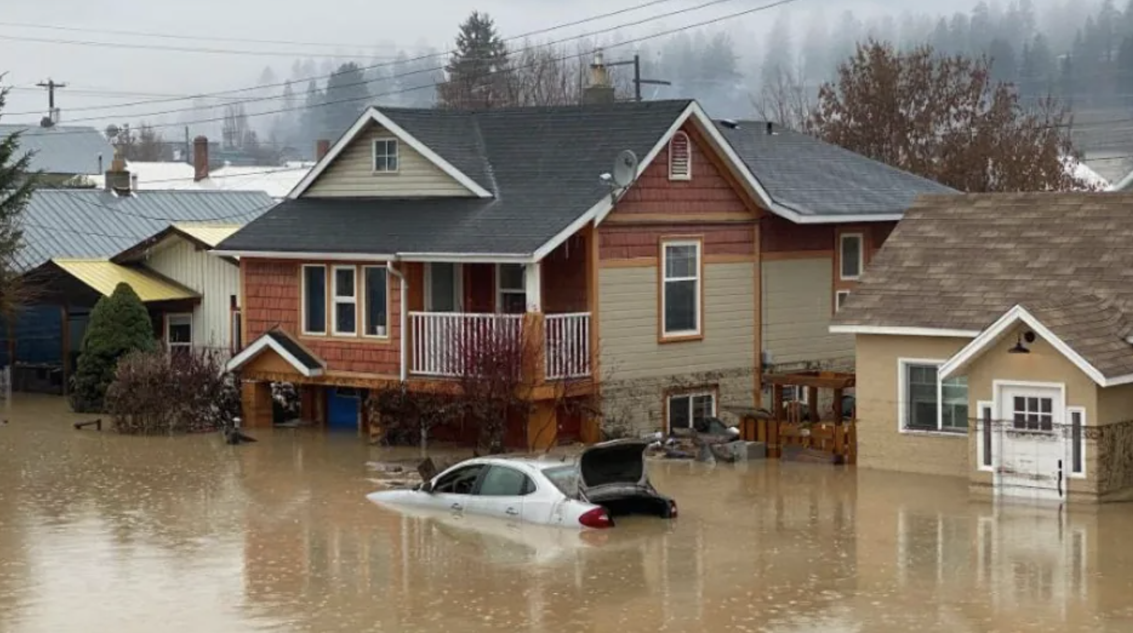 image of an vehicle in a flood with houses in the back.